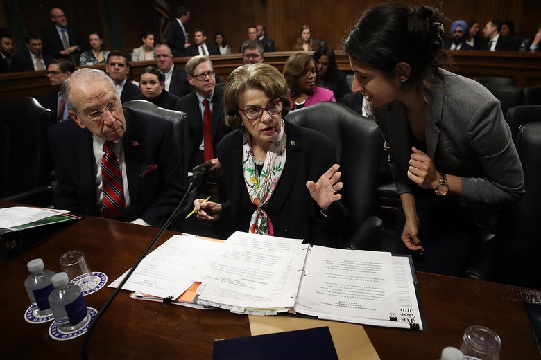 A staffer speaks to Sen. Dianne Feinstein at a committee hearing.